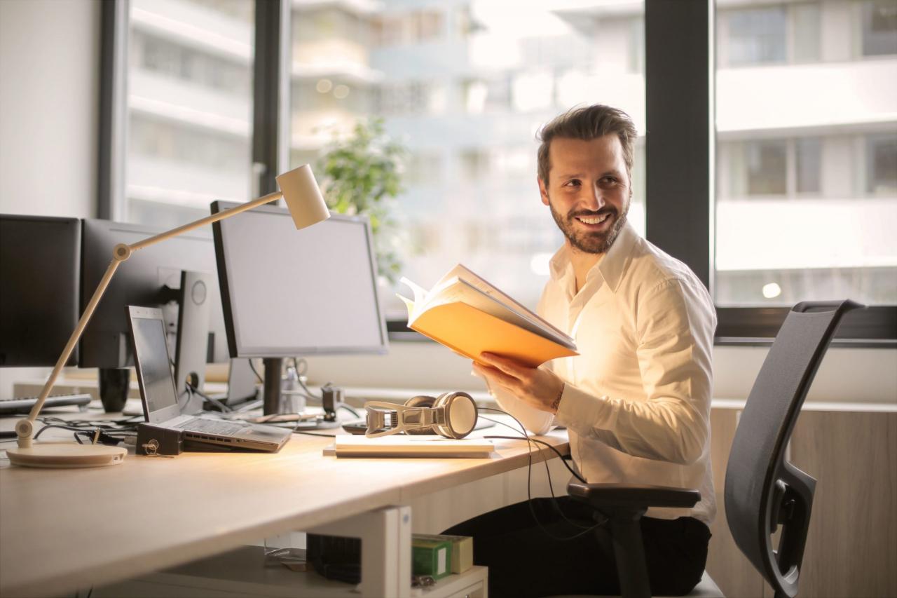 Man smiling sitting at desk working in front of a computer