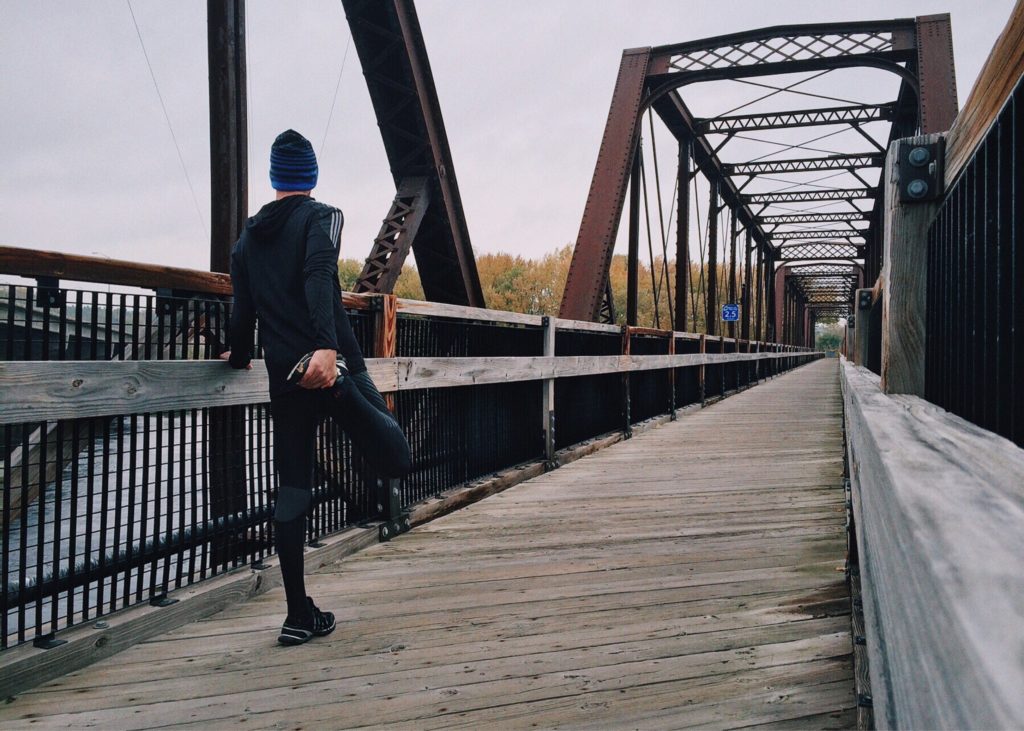 Man stretching on a bridge, about to exercise to help with his anxiety.